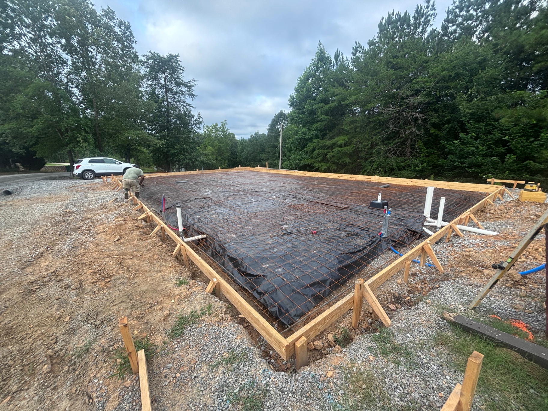 Concrete slab prep in Birmingham, AL — formed with rebar grid, vapor barrier, and plumbing stub-outs on compacted gravel base